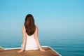 Lonely woman in white dress sitting on the pier looking at the sea Royalty Free Stock Photo