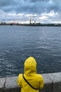 Lonely woman in yellow raincoat and hood standing on embankment Royalty Free Stock Photo