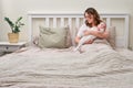 A lonely woman with a newborn baby is lying alone in an empty bed. Mom with a child in her arms in the bedroom Royalty Free Stock Photo