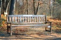 Lonely wooden bench with labels in a park on sunny autumn day