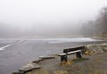 Lonely wooden bench in winter scenery by frozen lake in foggy rainy weather, bergen, norway Royalty Free Stock Photo