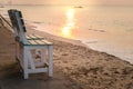 Lonely wooden chair on seashore at sunrise