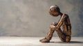 A lonely wooden human figure sits in a pose of despair. Copy-space Royalty Free Stock Photo