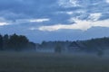 Lonely wooden rural house in the field. Evening fog. Royalty Free Stock Photo