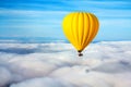 A lonely yellow hot air balloon floats above the clouds. Concept leader, success, loneliness, victory Royalty Free Stock Photo