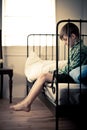 Lonely Young Boy Sitting on Bed Inside his Room Royalty Free Stock Photo
