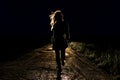 Lonely young frightened woman on an empty night road runs away in the light of the headlights of her car Royalty Free Stock Photo