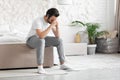 Lonely young man sitting on bed alone, copy space Royalty Free Stock Photo