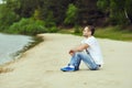 Lonely young man sitting near a lake in a forest Royalty Free Stock Photo