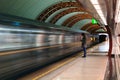 Lonely young man with smartphone shot from profile at subway station with blurry moving train in background. Royalty Free Stock Photo