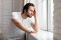 Lonely young man standing by window, copy space Royalty Free Stock Photo
