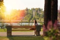 Lonely young woman sitting on a bench in the park near the lake on sunset Royalty Free Stock Photo