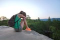 Lonely young woman sitting depressed on hillside trail on warm summer evening. Lost female hiker crying on rocky cliff Royalty Free Stock Photo