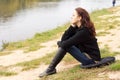 Lonely young woman sitting on a lake shore Royalty Free Stock Photo