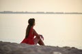 Lonely young woman sitting on ocean sandy beach by seaside enjoying warm tropical evening Royalty Free Stock Photo