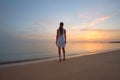 Lonely young woman standing on sandy beach by seaside enjoying warm tropical evening Royalty Free Stock Photo