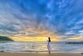 Lonely young woman stands alone on the beach looking towards the end of the vast horizon