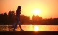 Lonely young woman walking alone on lake shore enjoying warm evening. Wellbeing and relaxing in nature concept Royalty Free Stock Photo