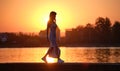 Lonely young woman walking alone on lake shore enjoying warm evening. Wellbeing and relaxing in nature concept Royalty Free Stock Photo