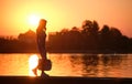 Lonely young woman walking alone on lake shore enjoying warm evening. Wellbeing and relaxing in nature concept Royalty Free Stock Photo