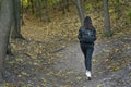 Lonely young woman walking in the forest and enjoys autumn. Girl walks outdoor, fallen leaves in park Royalty Free Stock Photo