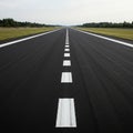 Long asphalt runway with white dashed centerline markings extending into the dista Royalty Free Stock Photo