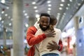Two happy multiracial friends hugging at airport, loving multiethnic couple embracing in terminal Royalty Free Stock Photo