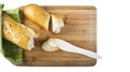 Long baguette and wooden butter knife on wooden cutting board