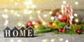 Long banner Christmas composition with and Shining lights. Red balls, Pine cones, lollipop, toy houses text Home on Wooden Table Royalty Free Stock Photo