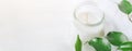 Long Banner for Organic Cosmetics Wellness White Candle in Glass Jar Fresh Tree Branches with Green Leaves on Wood Background. Spa