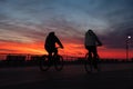 Long Beach, New York - December 13 2020 : Vibrant colorful sunset over a man ride biking on the boardwalk