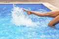 Long beautiful female feet and splashes of clear blue fresh water in pool. Woman`s legs sporting in water in swimming pool Royalty Free Stock Photo