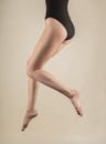 Long beautiful slender female legs hanging in the air in the jump. The girl is dressed in a black body. Isolated on a light Royalty Free Stock Photo