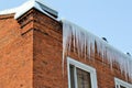 Long, big and dangerous icicles on a brick house roof Royalty Free Stock Photo