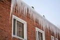 Long, big and dangerous icicles on a brick house roof Royalty Free Stock Photo
