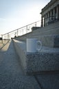 A long blank white coffee mug on the corner of the capitol steps