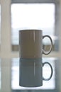 A long blank white coffee mug on the window table.