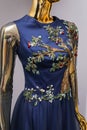 Long, blue designer, evening, women`s dress handmade on gold, glossy mannequin. With white and gold ornament in