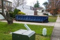 Long blue dumpster full of wood and other debris in the driveway in front of a house in the suburbs Royalty Free Stock Photo