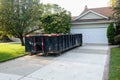 Long blue dumpster full of wood and other debris in the driveway in front of a house in the suburbs that is being renovated Royalty Free Stock Photo
