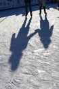 Long blue shadows on the ice at the ice rink from a group of skaters. Winter sunny day. Outdoor activities concept. Royalty Free Stock Photo