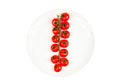 Long branch of organic ripe fresh cherry tomatoes on a white plate isolated on a white background. Royalty Free Stock Photo