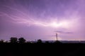 Long, branched, powerful lightning bolts strike down behind the trees. Dramatic lightning bolt. Royalty Free Stock Photo