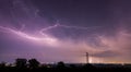 Long, branched, powerful lightning bolts strike down behind the trees. Dramatic lightning bolt. Royalty Free Stock Photo