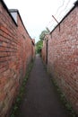 A long brick alley way with barbed wire on one side