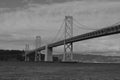 a long bridge crosses over the water under cloudy skies in black and white Royalty Free Stock Photo