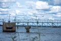 A long bridge over calm waters with birds perched on its railing under a cloudy sky in a tranquil setting Royalty Free Stock Photo