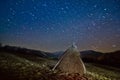 Long bright star tracks in clear deep blue night sky, mysterious landscape with a haycock in a farm field Royalty Free Stock Photo