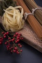 Long brown pasta and pasta with different  shapes and colors with a bowl of pepper. Royalty Free Stock Photo