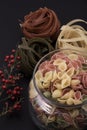 Long brown pasta and pasta with different  shapes and colors with a bowl of pepper. Royalty Free Stock Photo